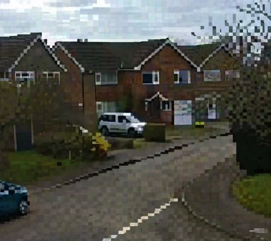 Grainy, low resolution footage of the same residential street from an old analogue CCTV camera